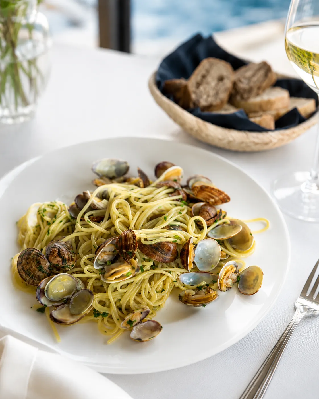 Spaghetti alle vongole serviti su tavolo bianco vista mare