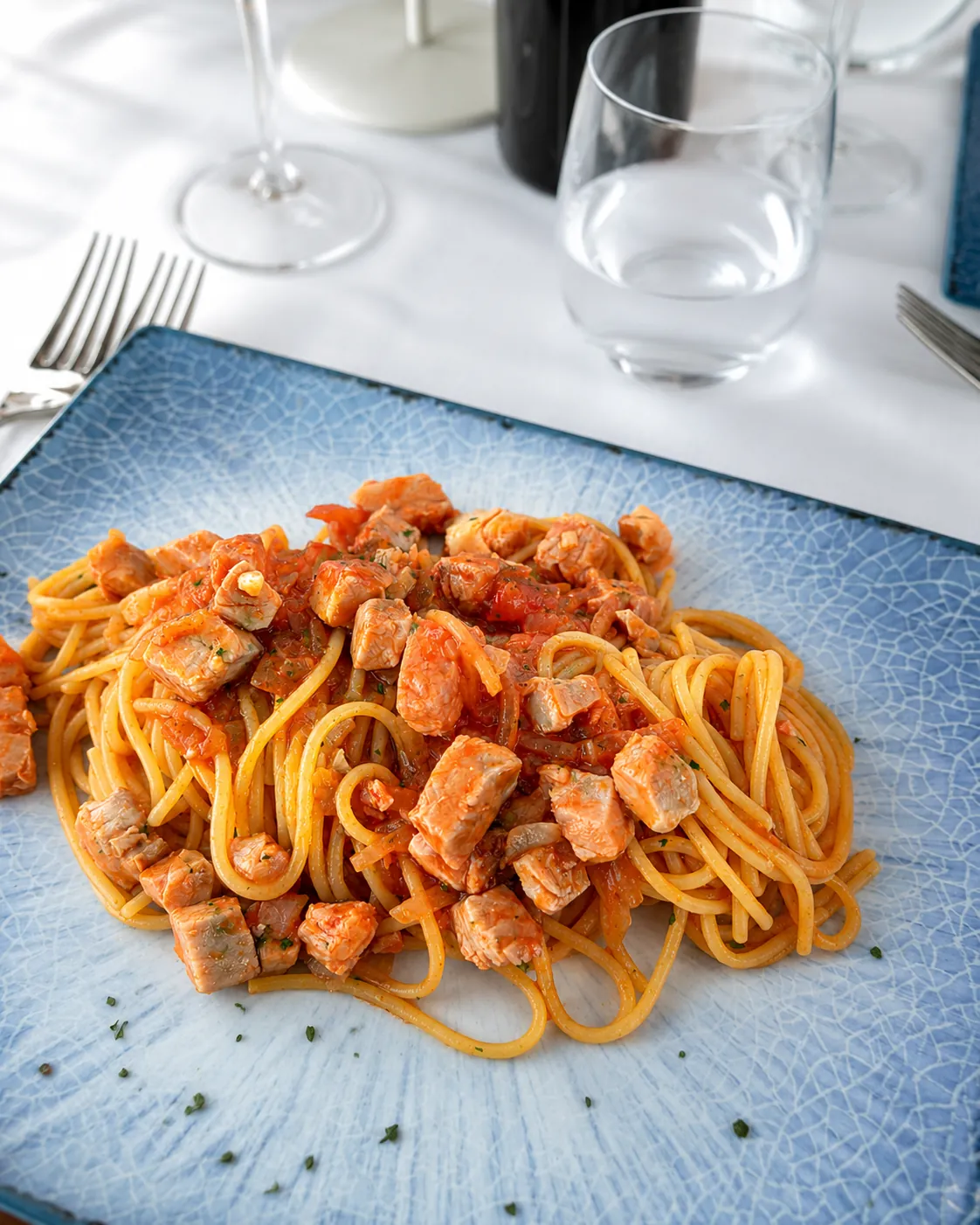 Pasta al pomodoro e pesce servita su piatto azzurro